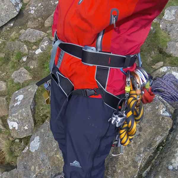 Side-on image showing the DMM Super Couloir being worn, clearly showing the quick release leg buckles, double back buckle waist closure and the simple waist attachment through the belay loop.