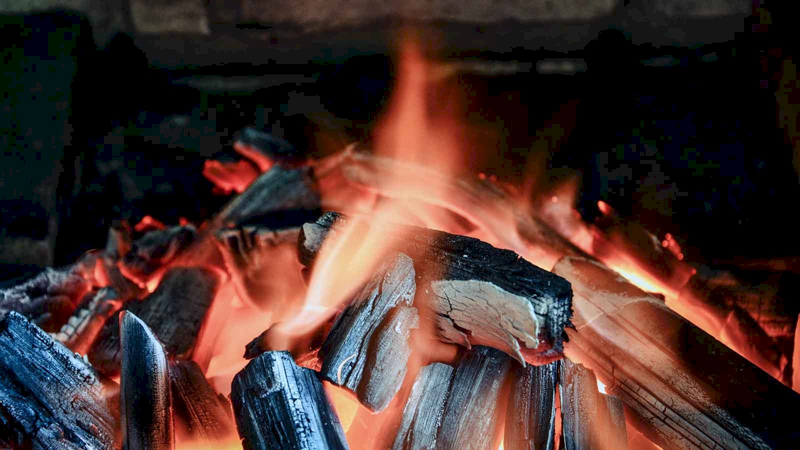 Image showing a warming log fire against a brick wall background.